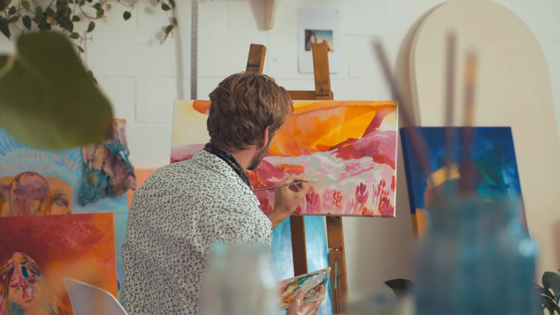 Artist painting an abstract canvas inside a working studio