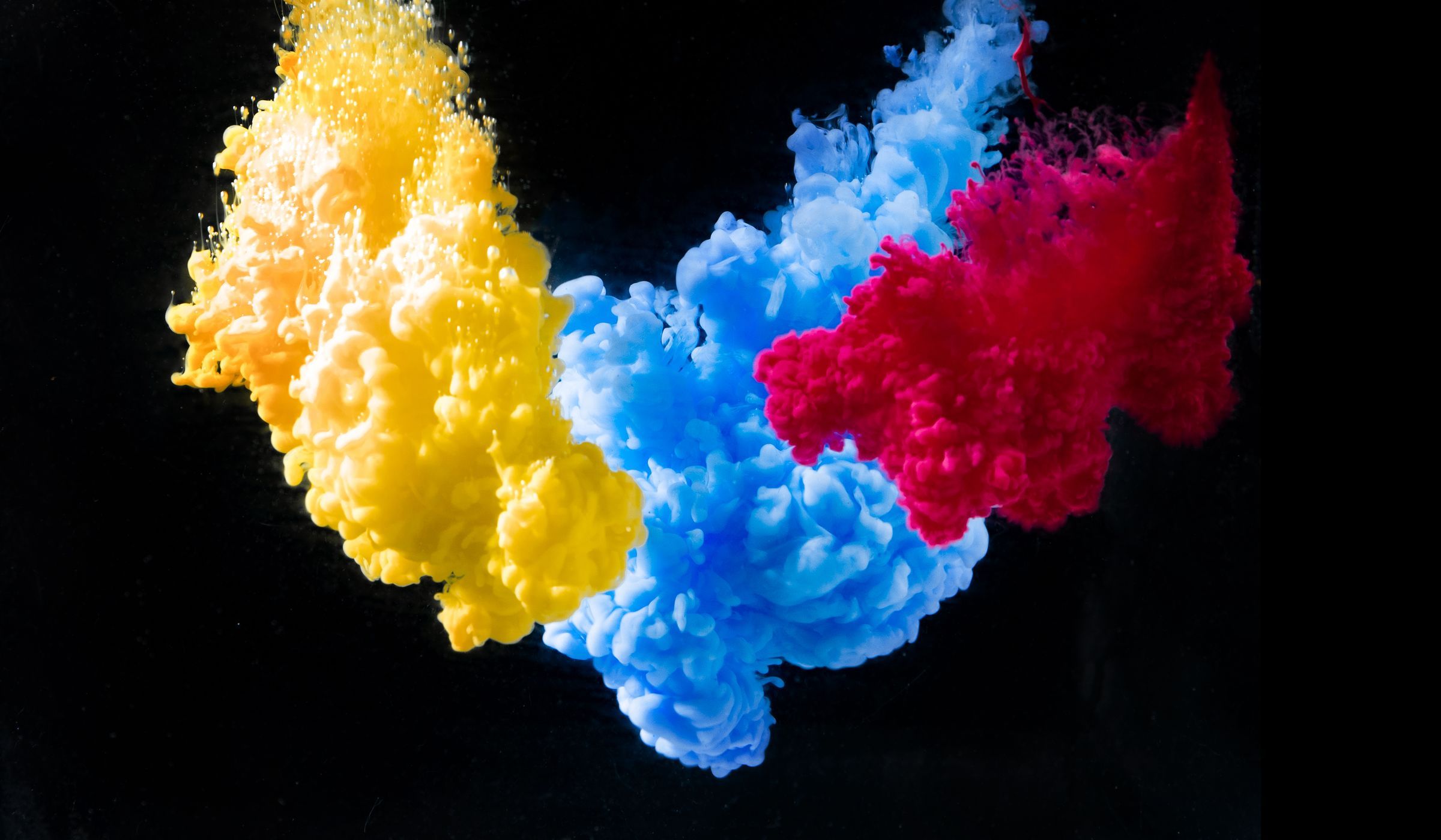 Vivid yellow, blue and red ink against a dark background