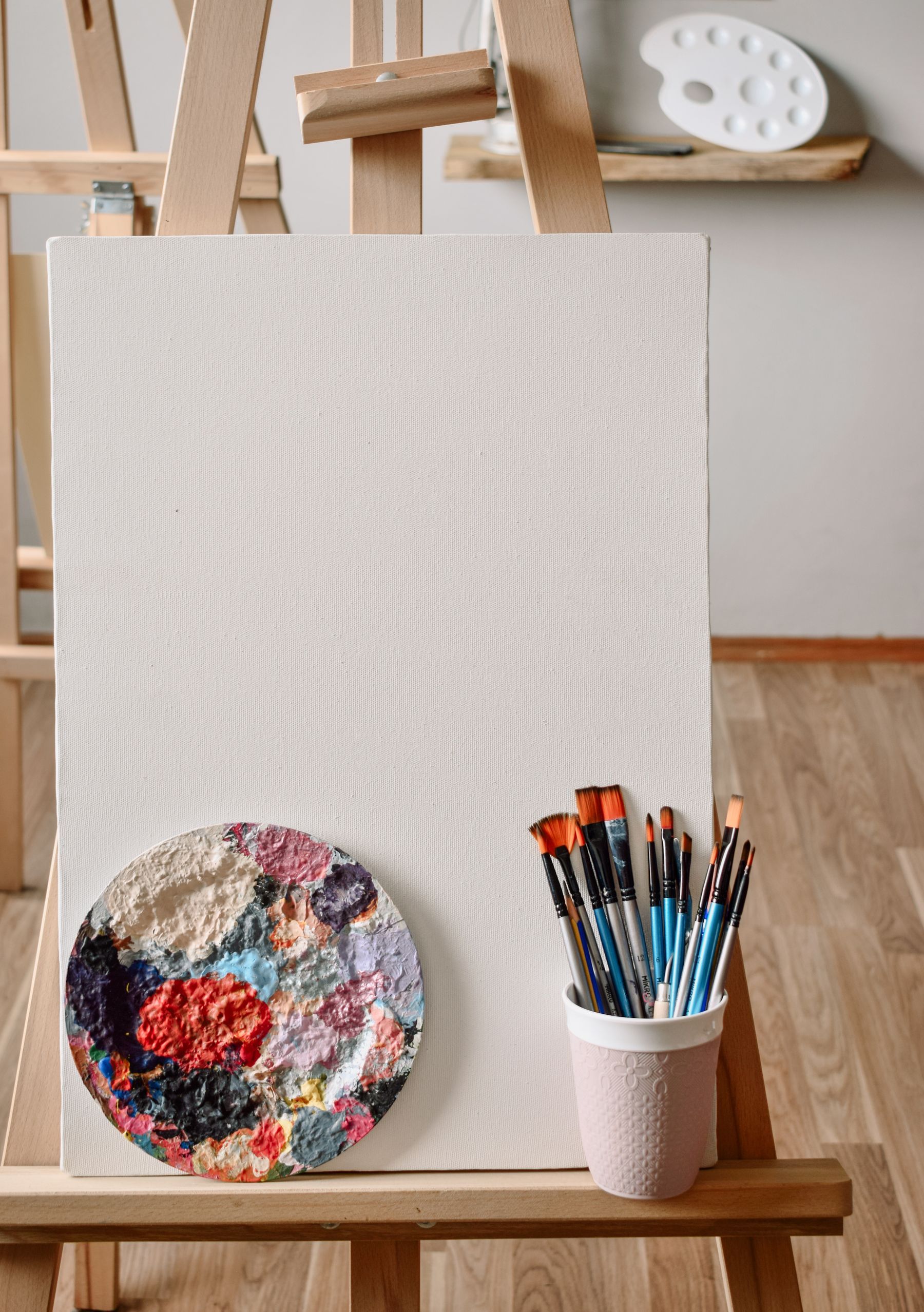 A blank canvas on an easel with brushes and a palette, ready for a new painting