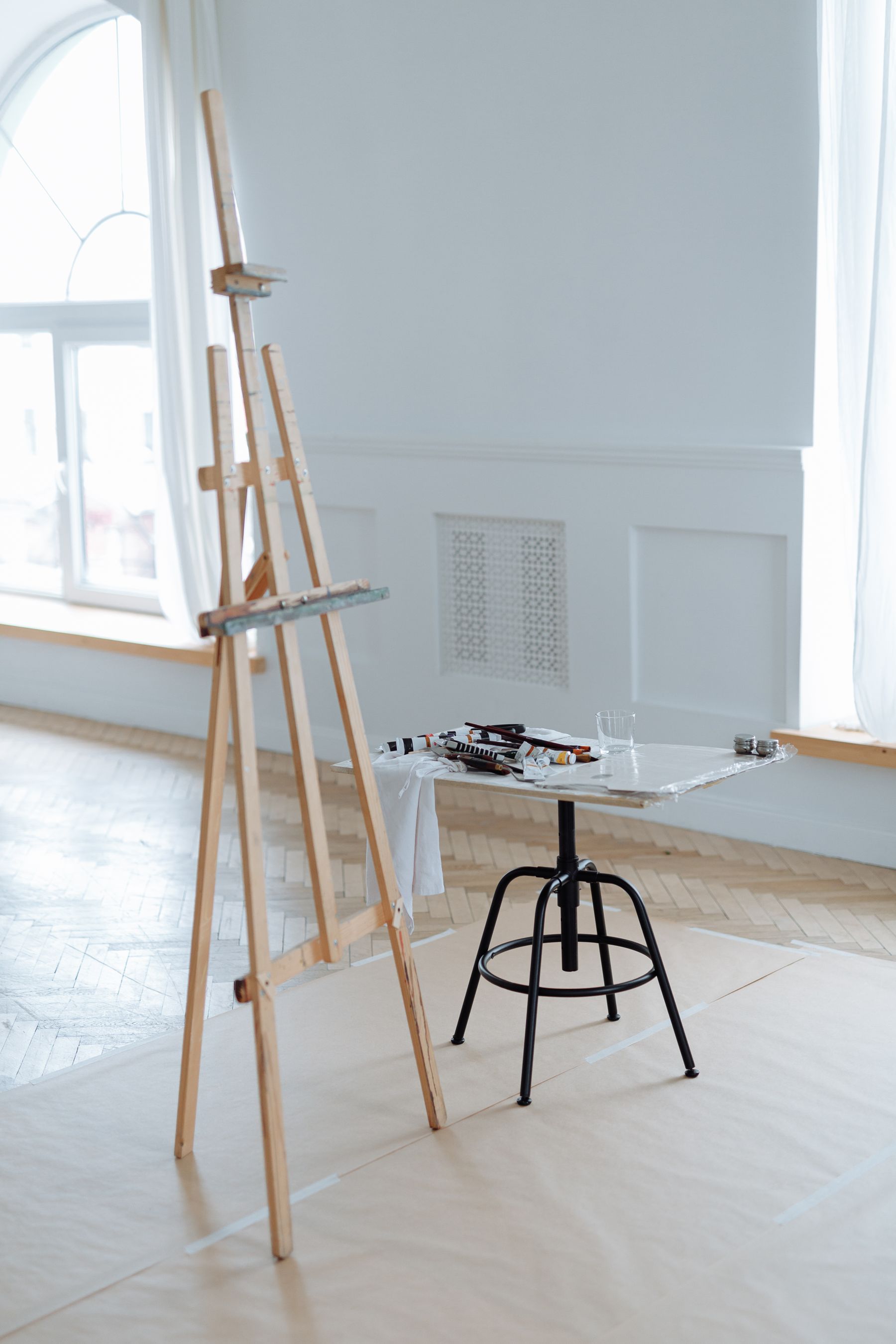 An easel and painting materials in a light-filled workshop